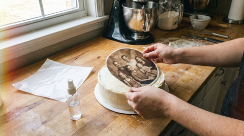 Placing a printed edible frosting sheet onto a buttercream cake in a home kitchen