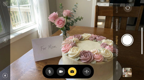 Round cake with buttercream flowers in pink and mauve on a dining table